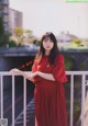 A woman in a red dress standing on a balcony.