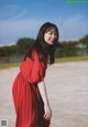 A woman in a red dress standing on a beach.