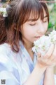 A woman in a blue kimono holding a bunch of white flowers.