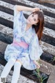 A woman in a blue and pink dress sitting on some steps.