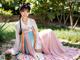 A woman in a pink and blue hanbok sitting on the ground.