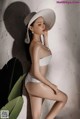 a woman in a white bikini and hat posing for a picture