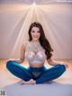 A woman sitting in a yoga pose on a white surface.