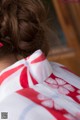 A woman wearing a red and white kimono with a pink bow in her hair.