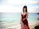 A woman in a red dress standing on a beach.