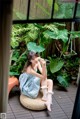 A woman sitting on a wicker chair in front of a window.