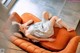 A woman laying on an orange couch with her legs crossed.