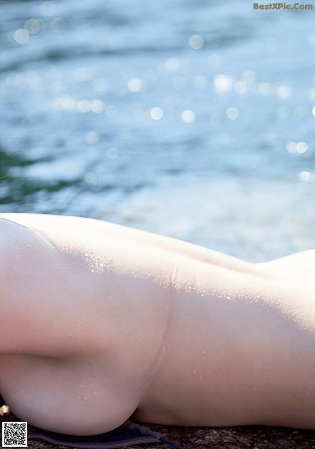 A woman laying on the beach next to the water.