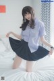A woman in a blue shirt and black skirt posing on a bed.