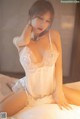 A woman in a white lingerie sitting on a bed.