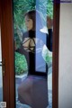 A woman in a black dress standing in front of a door.