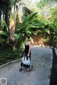 A woman in a black and white dress standing in a garden.