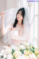 A woman in a wedding dress sitting on a window sill.