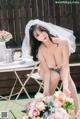 A woman in a wedding dress sitting on a table with flowers.