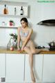 A woman sitting on top of a kitchen counter.