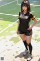 A woman in a soccer uniform standing on a soccer field.