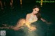 A woman in a white bikini sitting in a pool.