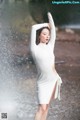 A woman in a white dress standing in the rain.