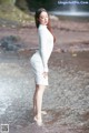 A woman in a white dress standing in the water.