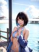 A woman in a blue bikini standing on a dock.