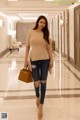 A woman walking down a hallway carrying a brown bag.