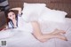 A woman in a white dress laying on a bed.