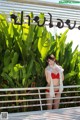 A woman in a red bikini standing in front of a sign.