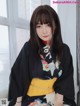 A woman in a black kimono sitting on a window sill.