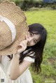 A young girl in a white dress holding a straw hat.