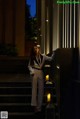 A woman in a white suit standing on some steps.