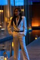 A woman in a white suit standing next to a pool.