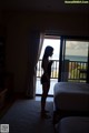 A woman standing in a hotel room looking out the window.