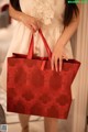 A woman in a white dress holding a red shopping bag.