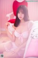 A woman in a pink lingerie sitting on a bed.