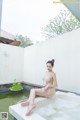 A woman sitting in a bathtub with foam on her feet.