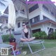 A woman sitting on a lounge chair in front of a house.